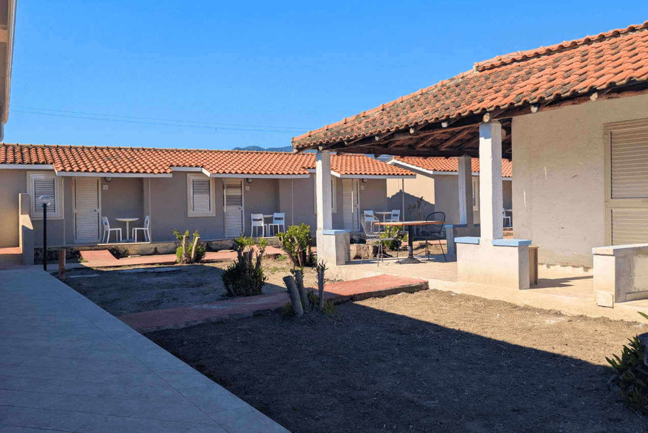 File di bungalow moderni con patio privato e sedie, circondati da un giardino curato in un resort a Patti, Sicilia