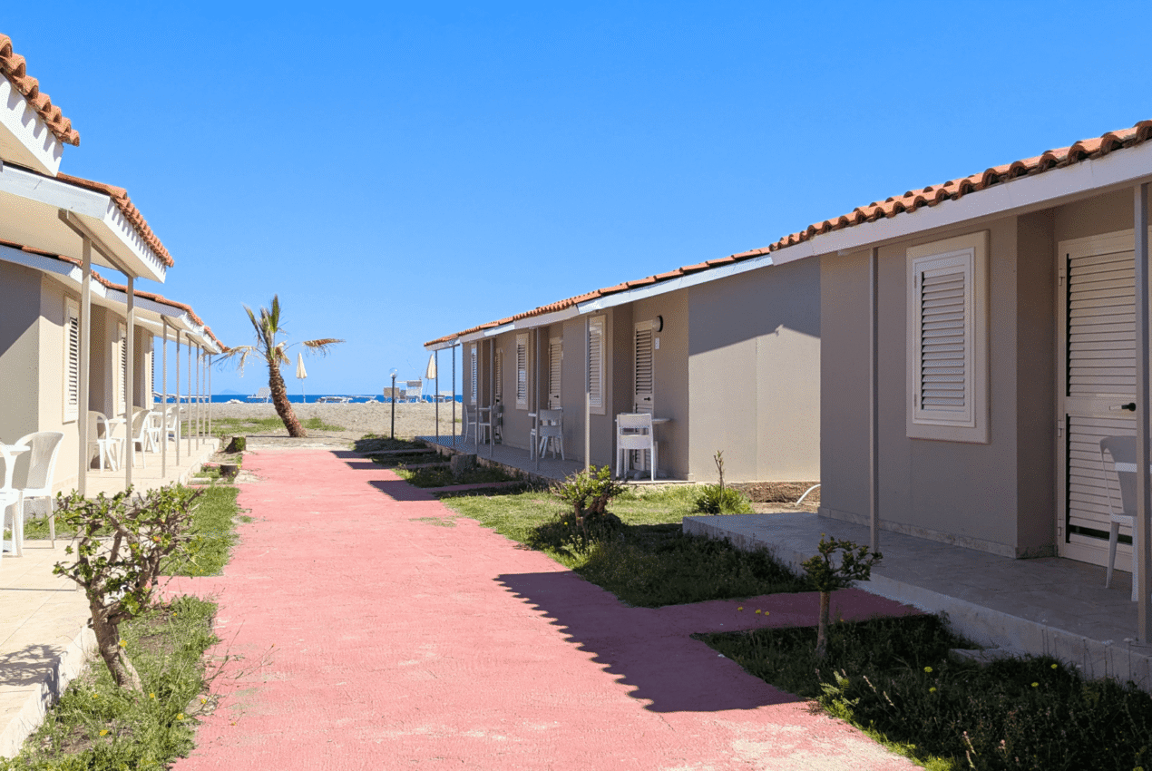 Primo piano di bungalow con patio arredato e vista sul mare cristallino della Sicilia e sulle Isole Eolie in lontananza, Patti