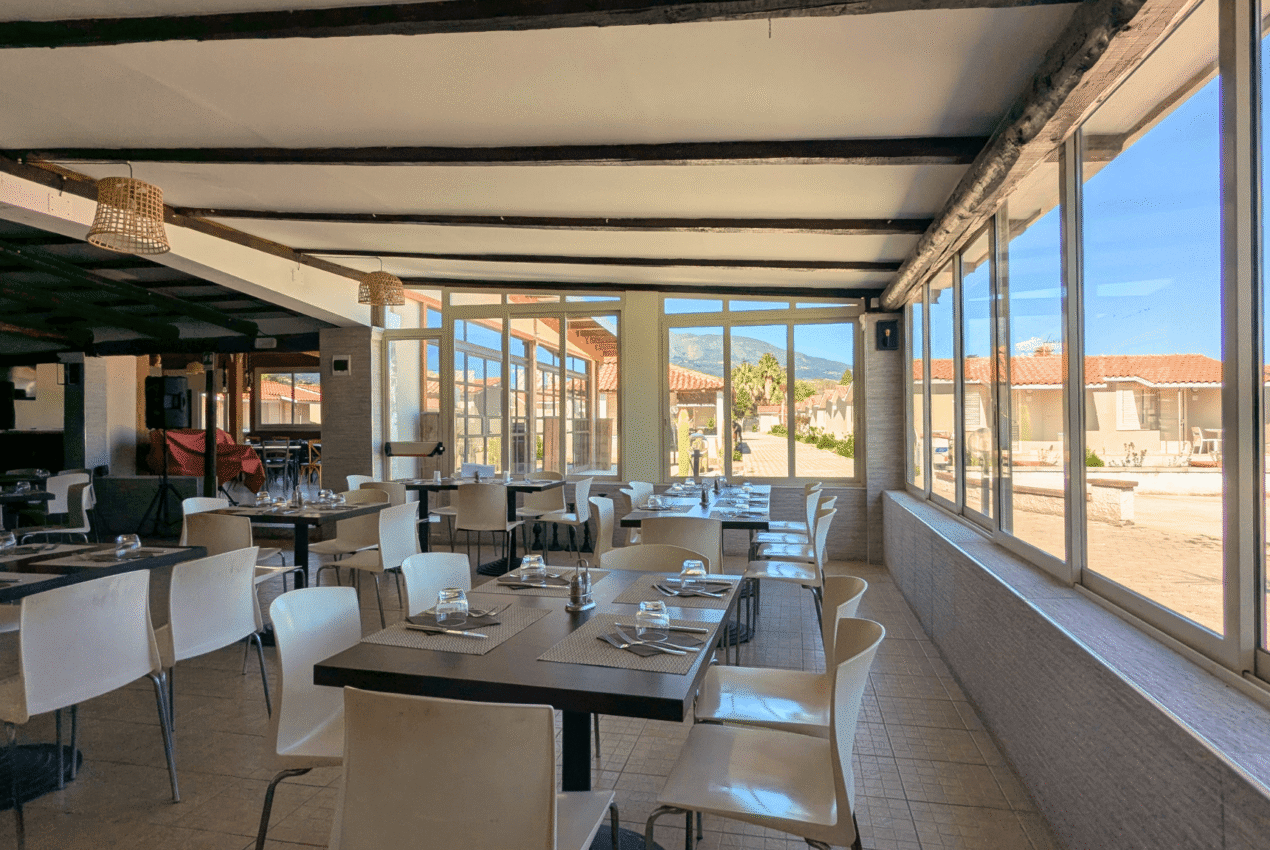 Sala ristorante del Patti Beach Resort con ampie vetrate vista mare, tavoli apparecchiati e soffitto con travi a vista per pranzi panoramici a Patti