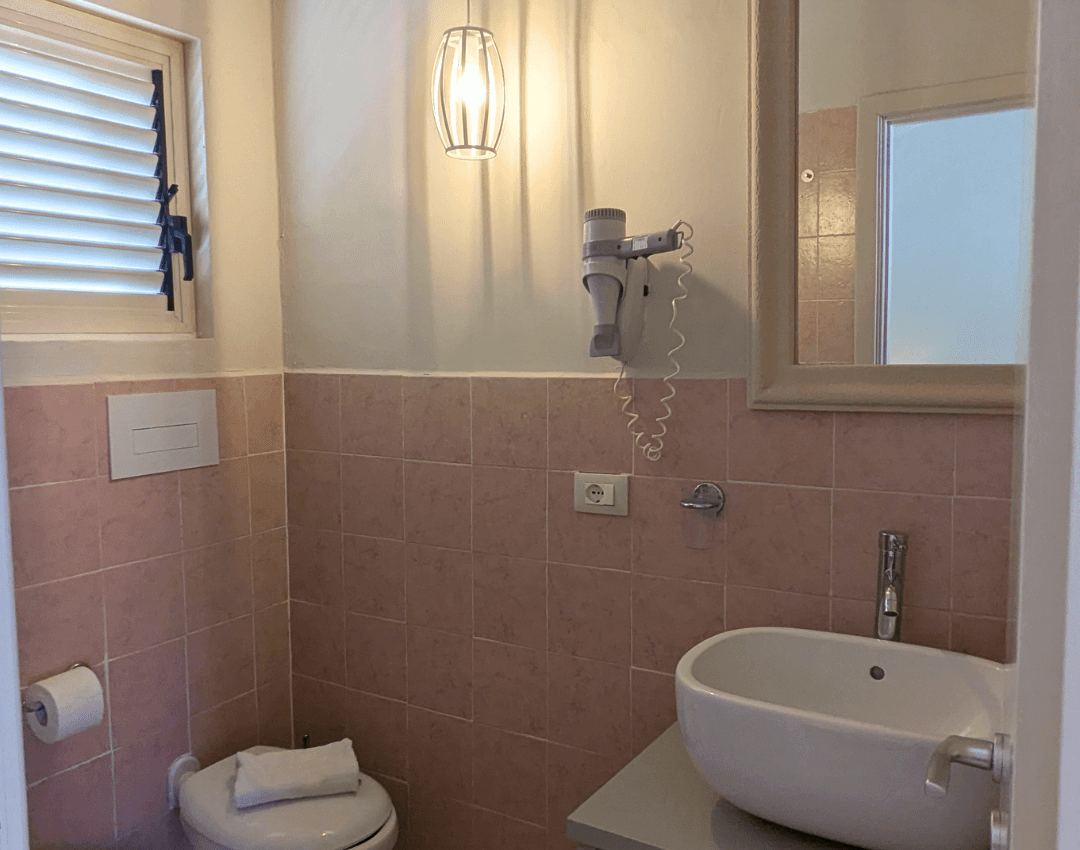 Bagno privato della camera del resort dotato di lavabo moderno, specchio e rivestimenti nei toni del rosa