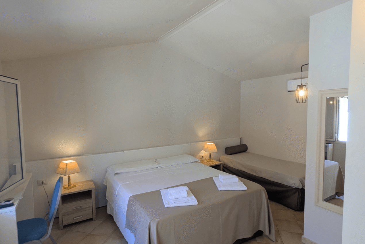 Camera tripla dell'hotel con letto matrimoniale, un letto singolo aggiuntivo e armadio bianco a muro
