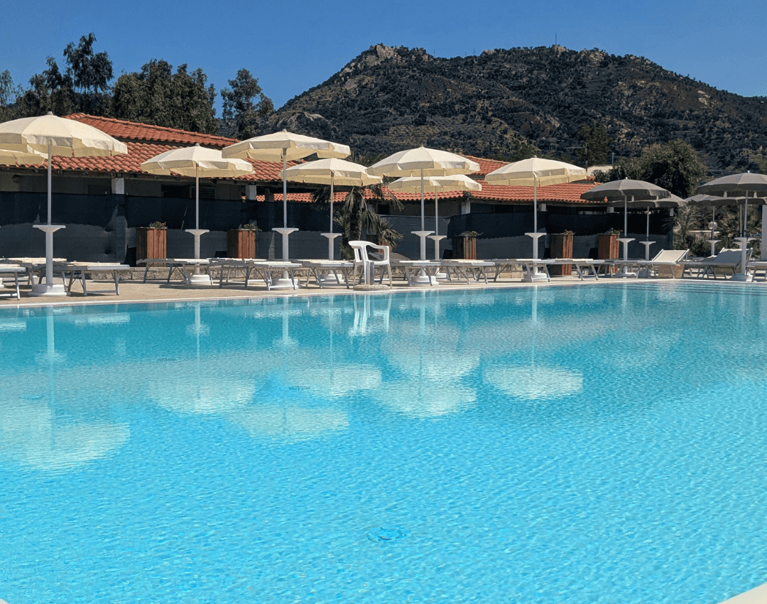 Inquadratura verticale della piscina del villaggio turistico con ombrelloni e zona solarium